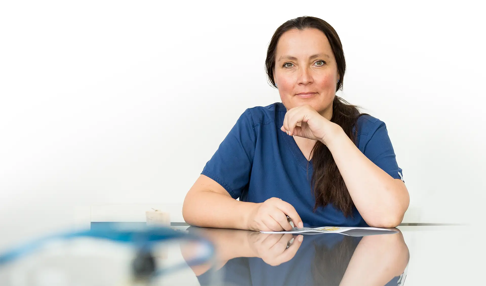 Dr. Maike Jörck MSc sitzt an einem Glastisch in einem blauen Shirt